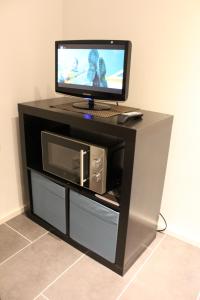 a black entertainment center with a monitor and a microwave at Arctic Jokasa Apartment in Rovaniemi