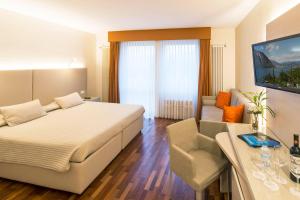 ein Schlafzimmer mit einem Bett, einem Schreibtisch und einem Sofa in der Unterkunft Hotel Campione in Bissone