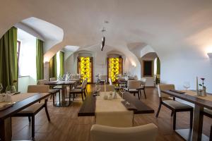 a dining room with tables and chairs and windows at Penzión Berg in Kežmarok