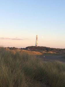 ホルムにあるAmelander Kaap 35の芝生に覆われた浜辺の上に座る灯台