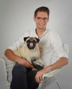 a man sitting in a chair with a pug dog at Boutique-Hotel "Stilvoll" in Andernach