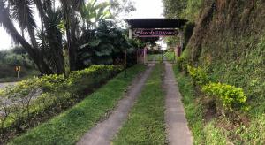 un camino de tierra con un letrero al costado de una colina en Finca Machangara, en Quimbaya