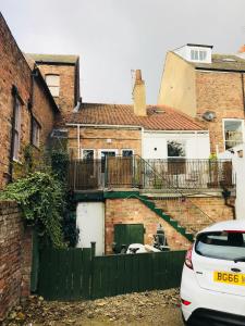 a brick house with a green fence and a white car at Gillygate Holiday Apartment in York