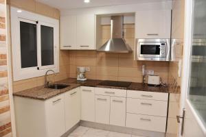 ロザスにあるRosesapparts Mairóの白いキャビネット、シンク、電子レンジ付きのキッチンが備わります。