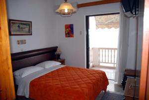 um quarto com uma cama com um cobertor laranja e uma janela em Antonios Rooms em Akrata