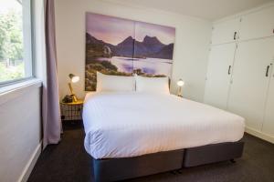 a bedroom with a large bed with a painting on the wall at CBD Apartments Launceston in Launceston