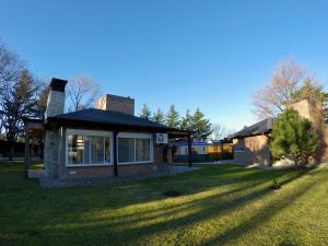 a house with a grass yard next to a building at Cabañas Latitud 38.15 in Sierra de la Ventana