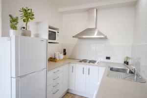 a white kitchen with a sink and a refrigerator at CBD Apartments Launceston in Launceston