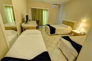 a hotel room with two beds and a television at Hotel Atlântico in Bombinhas