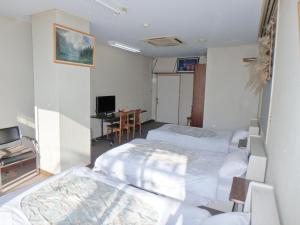 a hotel room with two beds and a desk at Azuma no Yu in Nagano
