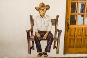 a man sitting on a wooden bench with a hat on at NaNa Vida Hotel Oaxaca in Oaxaca City