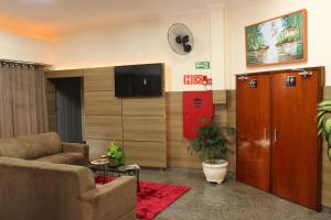 uma sala de estar com um sofá e uma televisão de ecrã plano em Hotel São Caetano em Ribeirão Preto