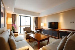 Ramada Nanjing في Jiangning: غرفة معيشة مع أريكة وتلفزيون