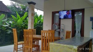 a dining room table and chairs with a television on the wall at Obama House Ubud in Ubud
