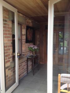 un porche con una pared de ladrillo y una mesa con flores en Pierrepoint Accommodation, en Hamilton