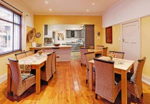 a dining room with tables and chairs and a kitchen at Tom's Guest House in Cape Town