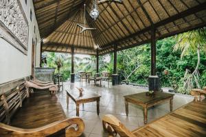 un pabellón con mesas de madera, bancos y árboles en Lembongan Cliff Villas, en Nusa Lembongan