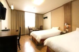 a hotel room with two beds and a television at Changwon Olympic Hotel in Changwon