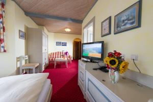 ein Hotelzimmer mit einem Bett und einem TV auf einer Kommode in der Unterkunft Hotel Sonnhof in Großarl