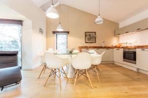 a kitchen with a dining room table and white chairs at The Cliffside Chalet - Modern 3BDR Riverside Home in Bath