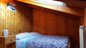 1 dormitorio con 1 cama en una pared de madera en Euroski B&B en Aosta