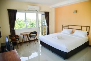 a bedroom with a bed and a table and a window at Thaimit Resort in Uttaradit