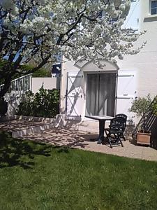 eine Terrasse mit einem Tisch und einem Stuhl unter einem Baum in der Unterkunft Maison d'hôtes Fortin Anita et Guy in Pouzauges