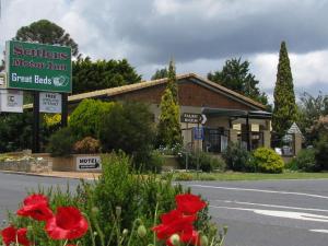 una señal para una posada de motores frente a un edificio en Settlers Motor Inn, en Tenterfield