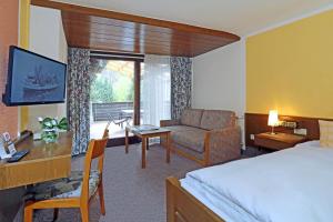 HeimbuchenthalにあるLandgasthof zur Lindeのベッド、デスク、ソファが備わるホテルルームです。