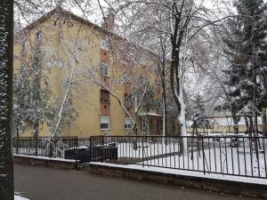 a black fence in front of a yellow building at Lia Apartman in Kiskunhalas