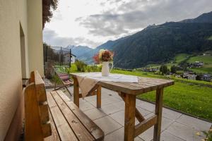 a wooden table with a vase of flowers on a balcony at Untersillerhof in Neustift im Stubaital