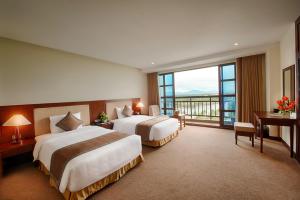two beds in a hotel room with a large window at Muong Thanh Holiday Hoi An Hotel in Hoi An +37 photos
