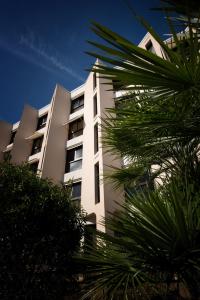 a white building with palm trees in front of it at Thermotel in Dax