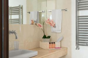 a bathroom with a sink and a mirror and flowers at Residenza Flaminio Gaio in Rome