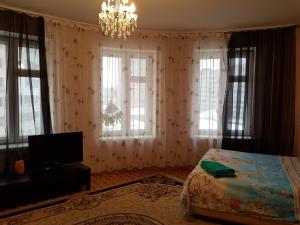 スタールイ・オスコルにあるКвартира на Степном с панорамными окнамиのベッドルーム1室(ベッド1台、シャンデリア、窓付)