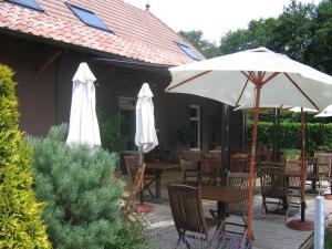 un patio con mesas, sillas y sombrillas en Hôtel Barbier des Bois, en Bruailles