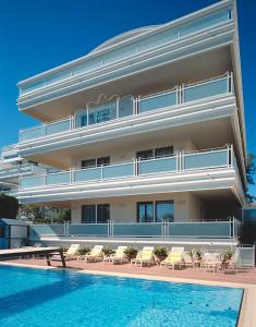 リッチョーネにあるResidence Riccione Beach Apartmentsの大きな建物で、目の前にスイミングプールがあります。