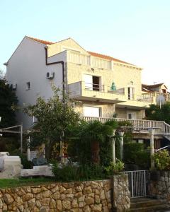 a large house with a stone fence in front of it at Apartments Miljas in Cavtat