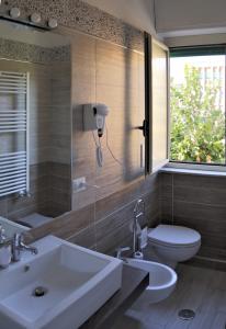 baño con lavabo y aseo y ventana en B&B Rosa, en Cosenza