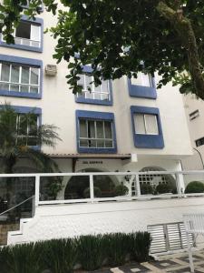 a white and blue building with a bench in front of it at Apartamento Zapata Guarujá in Guarujá