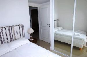 een witte slaapkamer met 2 bedden en een spiegel bij Stunning 2 Bed Apt on the seafront of Cannes in a high class secure building with swimming pool 463 in Cannes