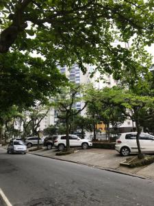 a street with cars parked in a parking lot with trees at Apartamento Zapata Guarujá in Guarujá