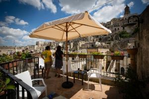 dos personas de pie en un balcón bajo una sombrilla en San Giovanni Vecchio - Residenza, en Matera