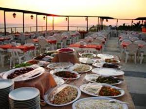 a long table filled with plates of food on a beach at West Ada Hotel&SPA in Kuşadası