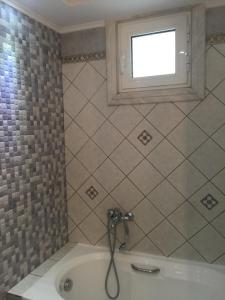 a bathroom with a bath tub with a window at Kavala Lux Apartment in Kavala +6 photos