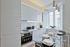 リスボンにあるBmyGuest - Exclusive Downtown Apartmentの白いキャビネットとガラスのテーブル付きのキッチン
