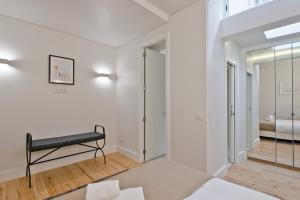 um quarto com paredes brancas e uma cama e um espelho em BmyGuest - Exclusive Downtown Apartment em Lisboa