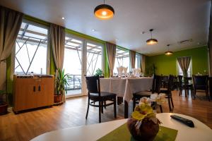 a dining room with a table and chairs and windows at Pensiunea La Broscuta in Cîmpia Turzii