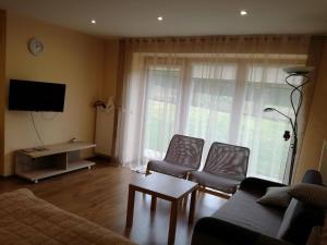 a living room with a couch and chairs and a tv at Apartamentai Klonio g. in Druskininkai