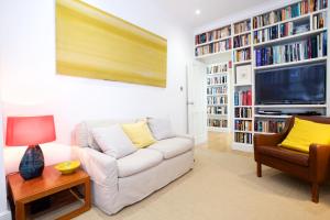 a living room with a white couch and a tv at English Retro 2BR apt, moments from Battersea Park in London